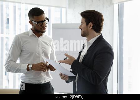 Due imprenditori multietnici discutono di un accordo in carica Foto Stock