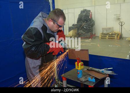 Saldatrice rettifica lamiera con smerigliatrice, preparazione saldatura, officina. 17 novembre 2021 Kiev Ucraina Foto Stock