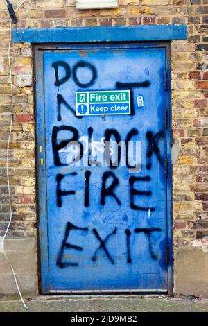 "Non bloccare l'uscita del fuoco", insegna o arte? Dietro la strada dei negozi, Penge, se London, UK. Foto Stock