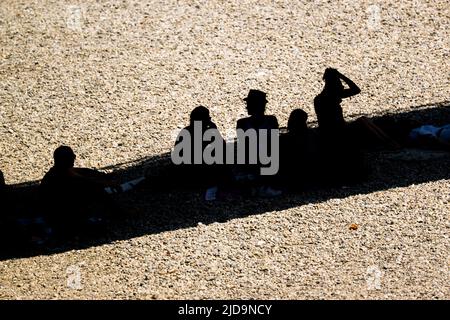 Monaco di Baviera, Germania. 19th giugno 2022. Su una panca di ghiaia, le persone godono l'ombra fornita da un ponte sopra di loro. Credit: Peter Kneffel/dpa/Alamy Live News Foto Stock