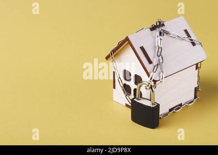 Arresto dell'alloggiamento. Casa del castello. Piccola casa giocattolo e una catena con un lucchetto. Sfratto per mancato pagamento. La porta chiusa a chiave della casa. Foto Stock