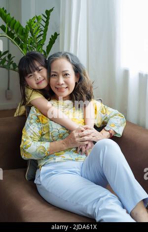Ritratto asiatico, nonna e nipote che fanno attività di svago e abbraccia per mostrare il loro amore e la cura per gli altri Foto Stock