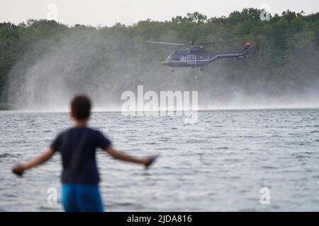 Seddin, Germania. 19th giugno 2022. Un elicottero della polizia federale prende l'acqua al lago Seddin per combattere gli incendi boschivi a Treuenbrietzen e Beelitz. Credit: Jörg Carstensen/dpa/Alamy Live News Foto Stock