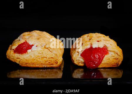 Due panini fatti in casa al forno con marmellata di fragole rosse, sfondo nero Foto Stock