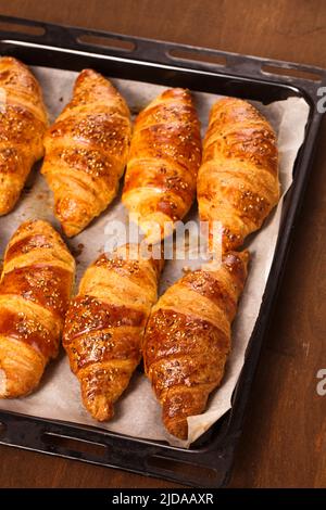 grandi croissant in lamiera da forno su sfondo di legno, vista dall'alto Foto Stock