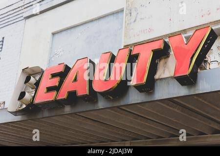 Vecchio segno DI BELLEZZA di fronte al grande magazzino abbandonato, scritta rossa. Foto Stock