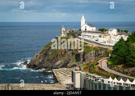 Pittoresca cappella con cementeria e un faro che domina il mare cantabrico nel villaggio di Luarca, Asturie, Spagna. Foto Stock