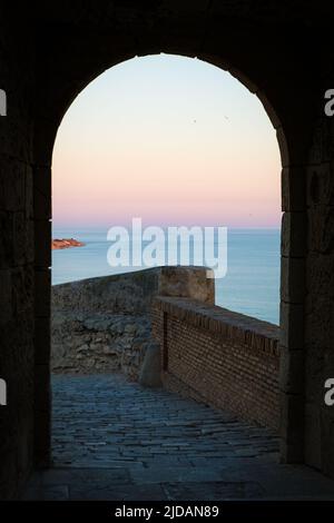 Tramonto visto attraverso l'arco del castello di Santa Barbara, Alicante, Spagna. Foto Stock