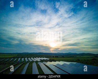 Moderni pannelli solari eco-compatibili per generare energia dai raggi del sole sono installati in prati infiniti con erba verde, sotto il cielo blu con brigh Foto Stock