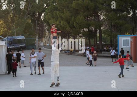 Catanzaro, Catanzaro, Italia. 19th giugno 2022. Un migrante ha visto tenere un bambino durante la visita del senatore. I migranti hanno visto giocare nel posto di Roccella. SOUAD SBAI (C) visto camminare nel posto di Roccella. Il senatore TONY CHIKE IWOBI, eletto per il Partito della Lega (Lega Nord), ha visitato il punto di primo soccorso dei migranti nel porto di Roccella Jonica, in Calabria. SOUAD SBAI, un politico italiano nato a Marocco, ha accompagnato l'IWOBI con rappresentanti regionali della Lega, un partito politico di destra, per valutare le condizioni critiche del posto di primo soccorso e le condizioni di lavoro delle forze di sicurezza locali. (Cod Foto Stock