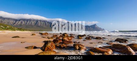 Spiaggia rocciosa lungo l'Oceano Atlantico a Kogel Bay con le montagne Kogelberg sullo sfondo; Kogel Bay, Capo Occidentale, Sud Africa Foto Stock