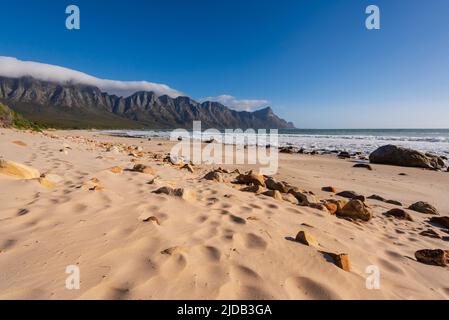 Spiaggia di sabbia lungo l'Oceano Atlantico a Kogel Bay con le montagne di Kogelberg sullo sfondo; Kogel Bay, Capo Occidentale, Sud Africa Foto Stock