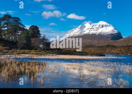 Guardando attraverso il piccolo lochen a Liathach coperto di neve, Glen Torridon; Scozia, Regno Unito Foto Stock