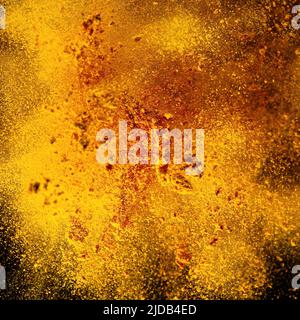 Esplosione, schizzi di curcuma su sfondo nero. India Seasoning. La polvere arancione della radice curmerica. Foto Stock