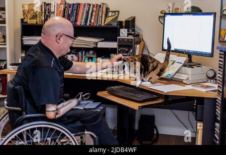 Uomo con amputazioni a doppio arto che lavora a distanza da casa su un computer; St. Albert, Alberta, Canada Foto Stock