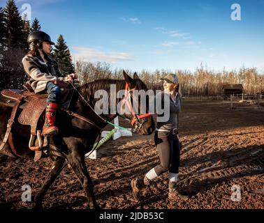 Un allenatore che lavora con una giovane ragazza con paralisi cerebrale durante una sessione di ippoterapia; Westlock, Alberta, Canada Foto Stock