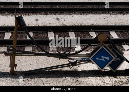 Primo piano di diversi segni metallici che si trovano lateralmente, che indicano la potenza di corrente elettrica e che mostrano un fulmine lungo le tracce di una strada ferroviaria Foto Stock