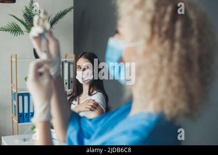 Immagine focalizzata sul paziente che guarda con paura l'infermiere che prepara il vaccino. Vaccinazione antinfluenzale. Iniezione sul braccio. Coronavirus, vaccino covid-19 Foto Stock