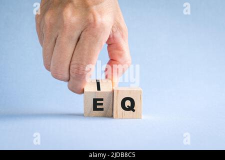 Le dita ribaltano il cubo di legno con la parola da IQ a EQ. Foto Stock