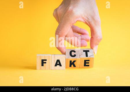 A mano flipping cubi di legno blocco, di fatto a falsa formulazione. Su sfondo giallo. Foto Stock