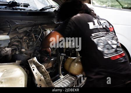 Il meccanico tailandese e tecnico professionale di riparazione e manutenzione del motore di automobile controlla la disponibilità e prepara il motore di servizio di riparazione dell'automobile alla ga locale Foto Stock