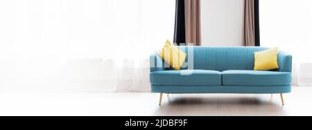 Ristrutturazione dell'appartamento. Elegante divano blu con cuscini gialli sullo sfondo delle finestre. Banner con spazio di copia. Il concetto di ipoteca e di noleggio hous Foto Stock