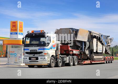 White Sisu 18E630 Truck of O.Rinne Oy che trasporta il frantumatore Kleemann su un rimorchio con caricatore basso presso la stazione di rifornimento di autocarri Shell. Forssa, Finlandia. Giugno 10, 2022 Foto Stock