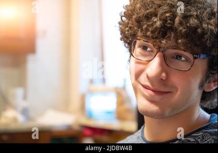 Ritratto di bel giovane uomo riccio e occhiali con un look di successo e positività. Spazio di copia. Foto Stock