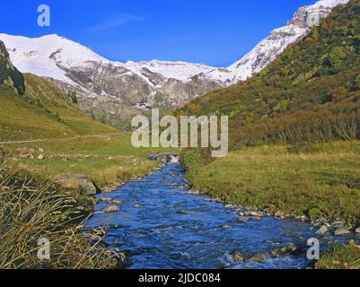 Francia, Savoia Beaufortain Massif torrente montano con cime innevate Foto Stock