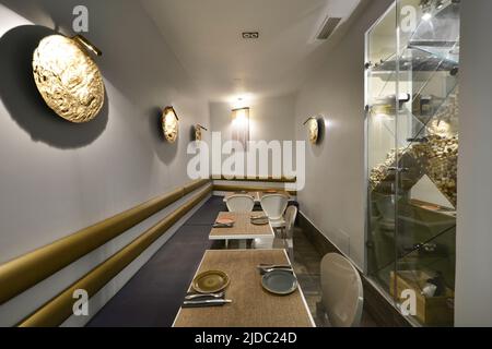 Sala da pranzo di un ristorante con piccoli tavoli quadrati, decorazione dorata e servizio di ristorazione set Foto Stock