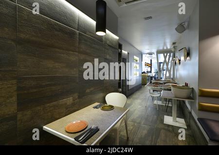 Sala da pranzo di un ristorante con tavoli quadrati, Falegnameria in legno bianco e piastrelle marroni Foto Stock