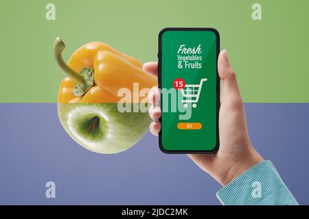 Donna che tiene uno smartphone e ordinare generi alimentari online, interfaccia utente con carrello Foto Stock