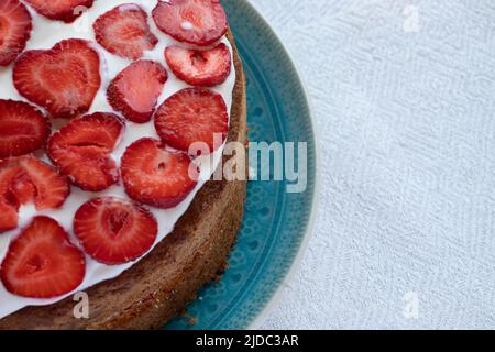 Torta con fragole e panna su piatto blu. Torta con strato di fragole estiva su sfondo bianco. Foto Stock