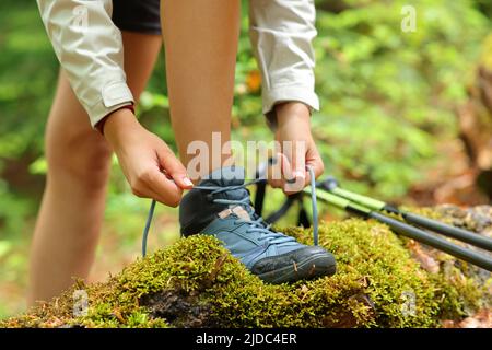 Primo piano ritratto di un trekking che lega scarpe di stivali in una foresta Foto Stock