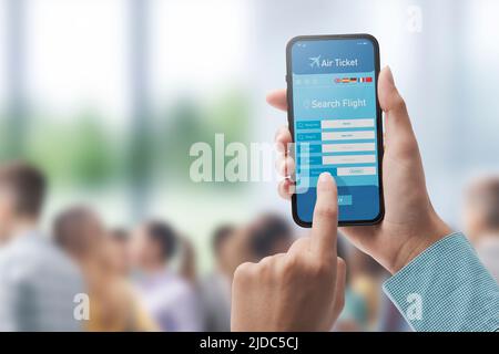 Utente che detiene uno smartphone e prenotare voli economici online, aeroporto in background, POV shot Foto Stock