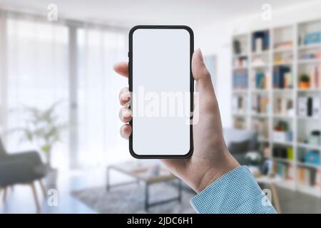 Donna che tiene uno smartphone con schermo vuoto e interno Foto Stock