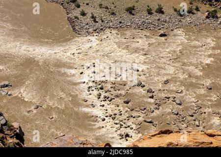 Acqua marrone e fangosa del fiume Orange nel Parco Nazionale Augrabies. L'acqua scorre velocemente e crea piccole rapide di acqua bianca Foto Stock