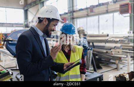 Responsabile tecnico e meccanico che esegue il controllo di routine in fabbrica industriale e che effettua videochiamate. Foto Stock