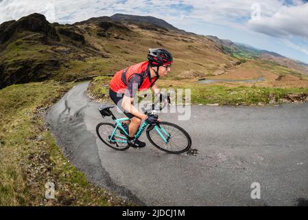 Un ciclista sportiva che guida l'Hardknott Pass nella Fred Whitton Challenge, sport ciclistico che si tiene nel Lake District inglese, Regno Unito. Foto Stock