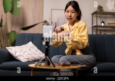 Korean Blogger Lady fare video al telefono utilizzando cosmetici interni Foto Stock