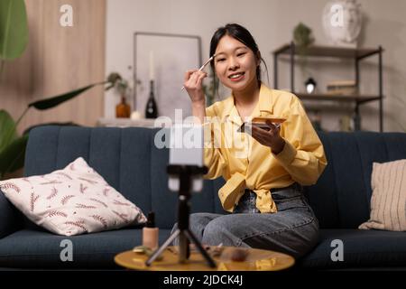 Asian Female Beauty Blogger fare Makeup filmare su smartphone in interni Foto Stock