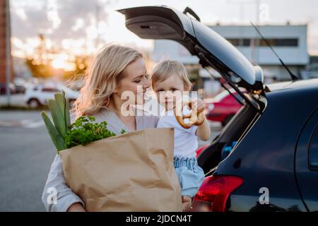 Donna con borse per la spesa vicino alla sua auto all'aperto Foto