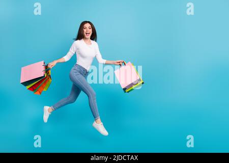 Foto di dolce cute signora vestita camicia bianca salto in alto corsa veloce shopping spazio vuoto isolato blu sfondo di colore Foto Stock