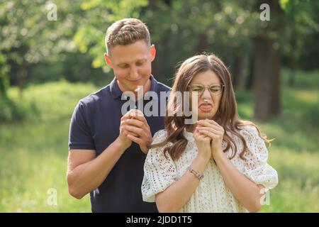 Uomo e donna che imbrogliano con fiore Chamomile. Girlfriend e boyfriend passeggiando, parco cittadino. Innamorarsi, umorismo foto Foto Stock