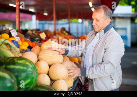Uomo di mezza età che acquista melone Foto Stock