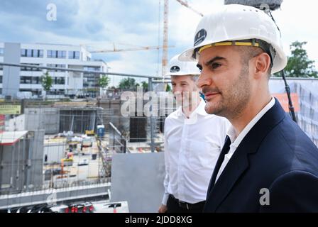 20 giugno 2022, Baden-Wuerttemberg, Tübingen: Danyal Bayaz (r, Bündnis 90/Die Grünen), ministro delle Finanze del Baden-Württemberg, guarda la prima parte della conchiglia durante la cerimonia di posa della pietra di fondazione per il campus di innovazione 'Cyber Valley' di Tübingen insieme a Boris Palmer (l, Bündnis 90/Die Grünen, sindaco di Tübingen. La "Cyber Valley" è la più grande cooperazione europea nel campo dell'intelligenza artificiale con partner di politica, scienza, imprese e società. Oltre al nuovo edificio Cyber Valley i, approvato nel 2016, il concetto generale Foto Stock