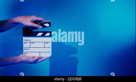 Scheda Clapper del film. La mano dell'equipaggio tiene il pannello in ardesia con pellicola di legno e plastica contro la fotocamera. Clapperboard di film usando nella produzione di video e nella vite prigioniera di film Foto Stock