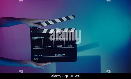 Scheda Clapper del film. La mano dell'equipaggio tiene il pannello in ardesia con pellicola di legno e plastica contro la fotocamera. Clapperboard di film usando nella produzione di video e nella vite prigioniera di film Foto Stock