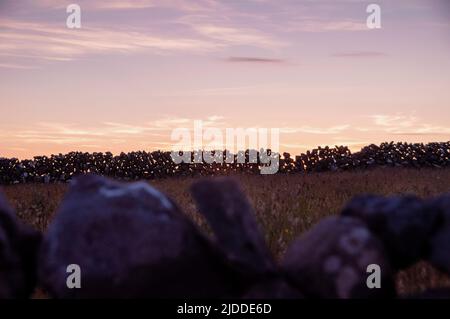 Pareti in pietra che si stagionano contro un tramonto di fine estate sull'isola di Aran di Inishmore a Galway Bay, Irlanda.