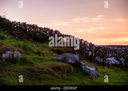Pareti in pietra che si stagionano contro un tramonto di fine estate sull'isola di Aran di Inishmore a Galway Bay, Irlanda.